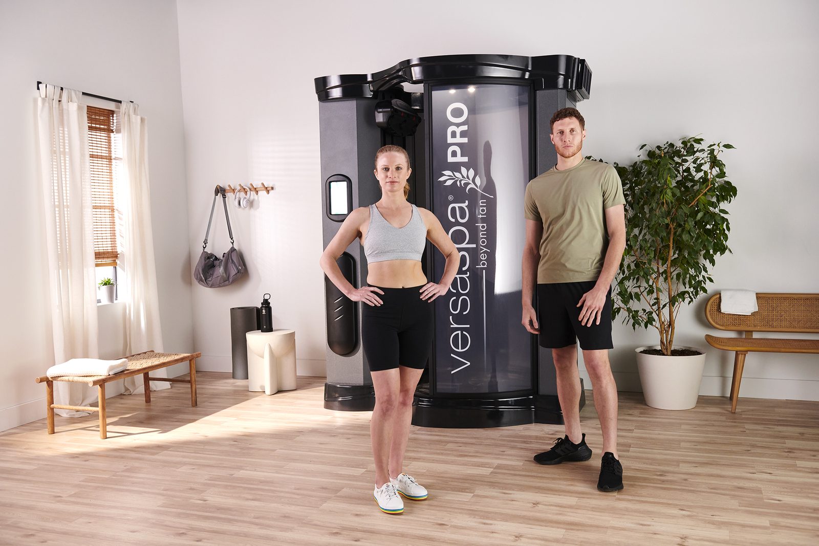 A man and woman beside the VersaSpa Pro spray tanning booth after their tan